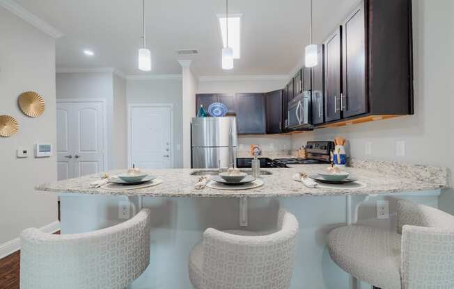 a kitchen with a granite counter top and a bar with three chairs