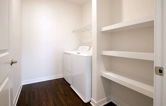 A white laundry basket sits on a shelf in a white room.