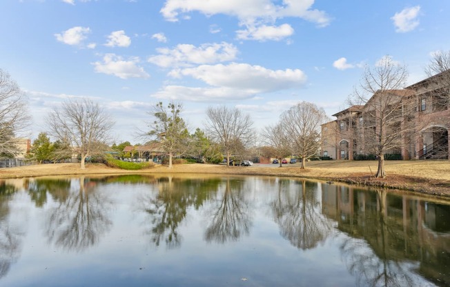a pond with buildings in the background and trees reflected in it