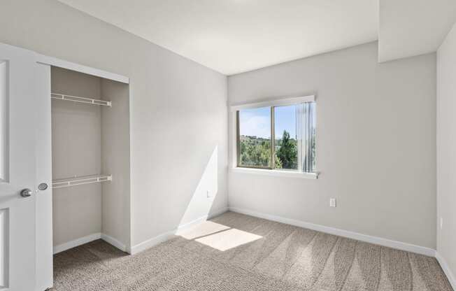 an empty bedroom with a large window and a closet