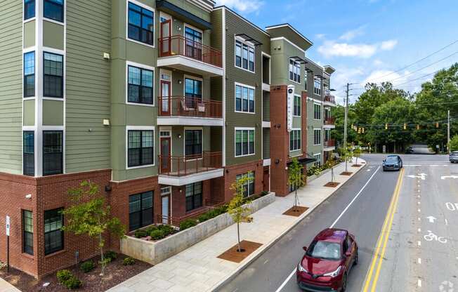 a street with a red car parked in front of an apartment building