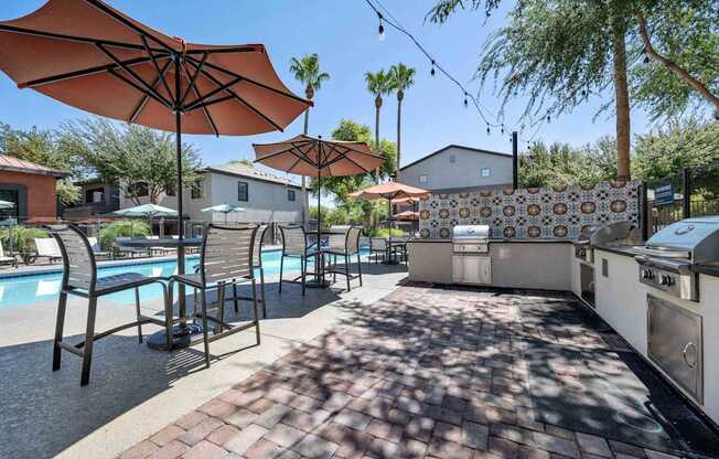 A poolside area with umbrellas and chairs. at Lazo Apartment Homes, Chandler, 85225