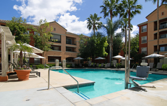 A pool surrounded by palm trees and umbrellas.