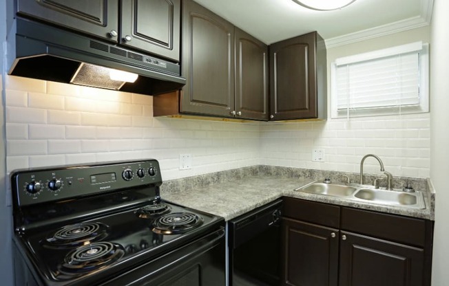 A kitchen with a black stove and brown cabinets.