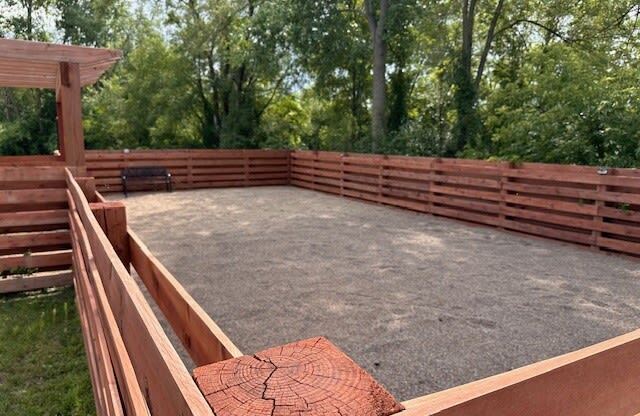 a backyard patio with a wooden fence and a sandbox