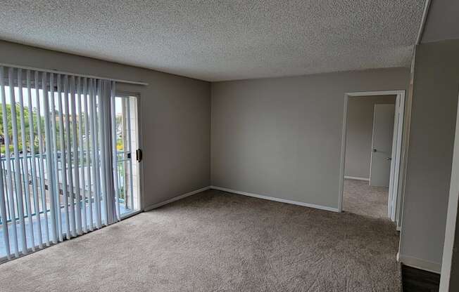 Carpeted living room with sliding glass doors to porch at La Mesa Village Apartments in La Mesa, California.