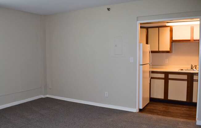 an empty living room and kitchen with a refrigerator and sink