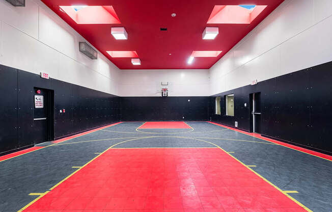 A basketball court with a red floor and a black wall.