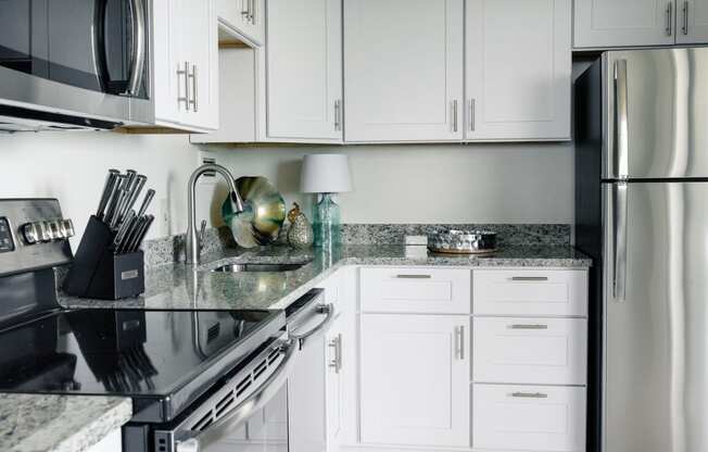 a kitchen with white cabinets and granite countertops at Hampton Plaza Apartments in Towson, MD 21286