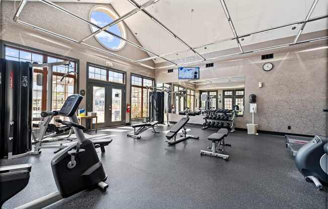 A gym with a variety of equipment including treadmills, weights, and exercise machines.