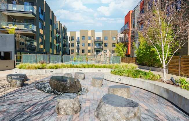 A courtyard with a fountain and stone benches in front of apartment buildings.