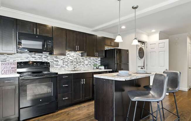 A modern kitchen with dark wood cabinets and a marble island.
