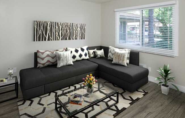 A black couch with pillows and a glass coffee table in front of it.