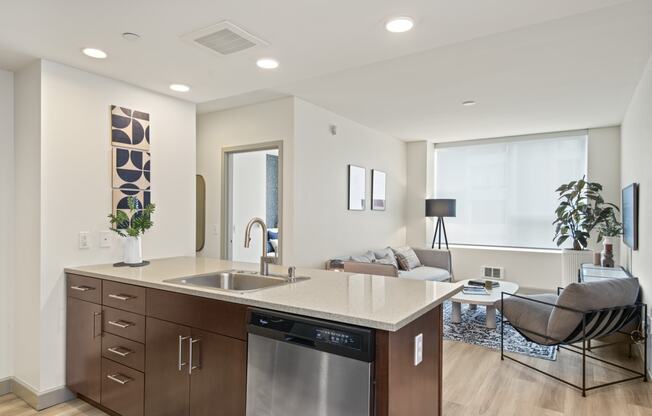a kitchen with a large center island next to a living room with a couch and a window