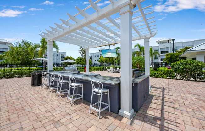 A white pergola is over a bar with stools.