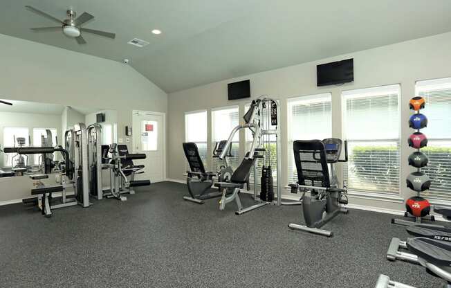 A spacious gym with a variety of equipment including a treadmill, a stationary bike, a rowing machine, a bench press, a squat rack, a leg press machine, a cable machine, a d