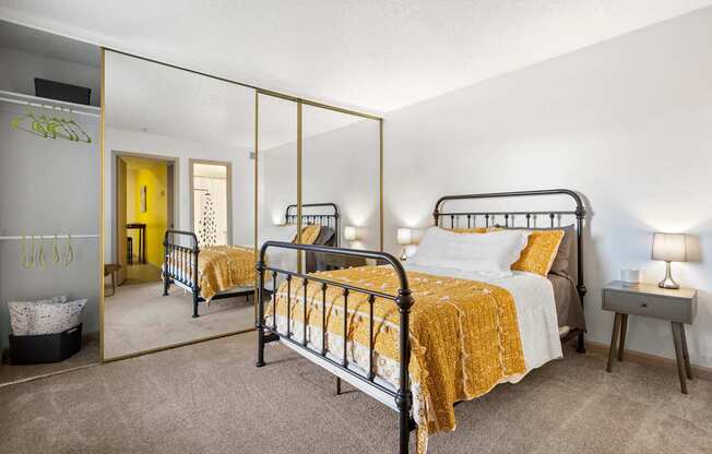 A bedroom with a bed, nightstand, and mirror.