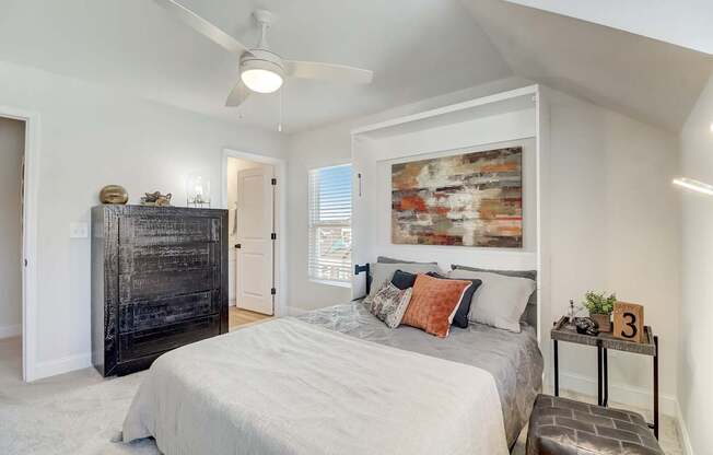 A bedroom with a bed, dresser, and a painting on the wall.
