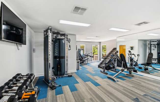 A gym with a variety of equipment including treadmills, weights, and exercise machines.