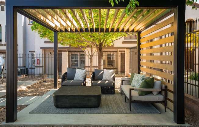 a patio with couches and chairs under a wooden pergola