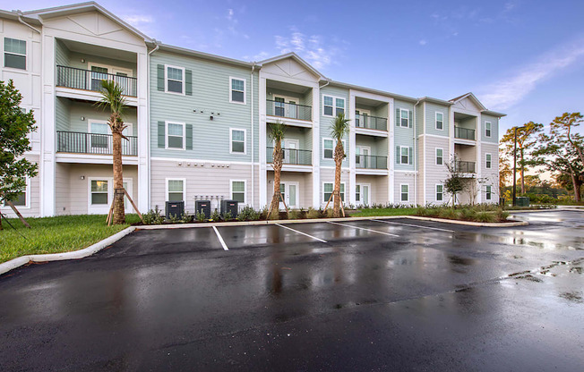 A large apartment complex with a parking lot in front.