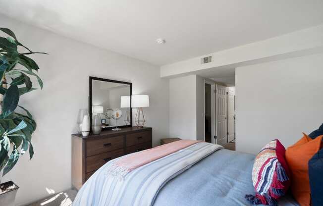 a bedroom with a bed and a dresser with a mirror