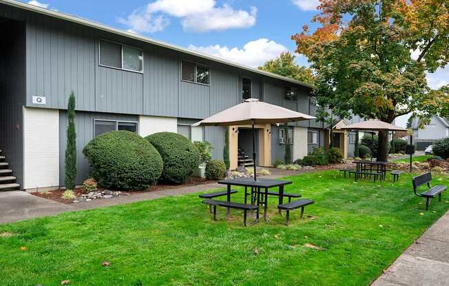 A grey building with a patio table and chairs in front of it.