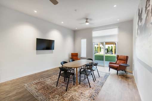 A room with a table and chairs and a television on the wall.