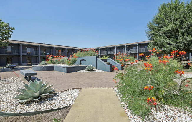 a courtyard with plants and flowers in front of a building