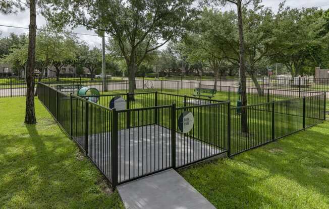 a wrought iron fence around a playground in a park