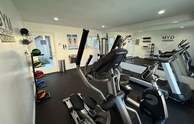 A gym with a variety of exercise equipment including treadmills, stationary bikes, and weight machines.