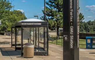 a bus stop with a bench and a trash can