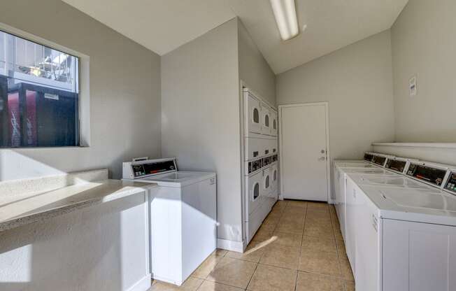 a laundry room with washes and dryers and a window