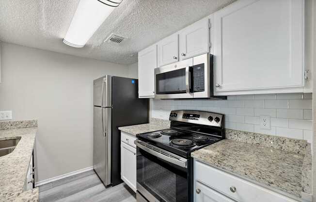 A kitchen with a black refrigerator, stove, and microwave.