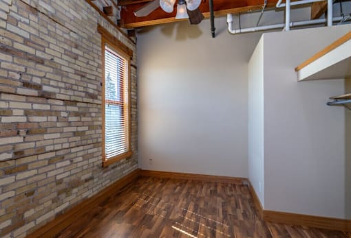 A room with a brick wall and wooden flooring.