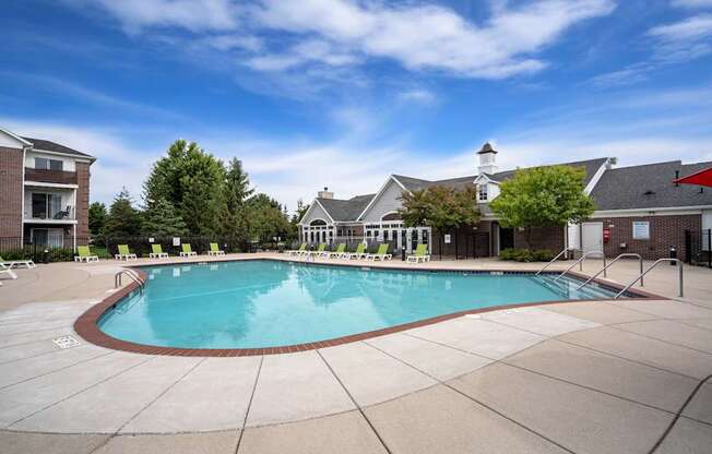 A large outdoor swimming pool surrounded by a concrete patio and buildings.