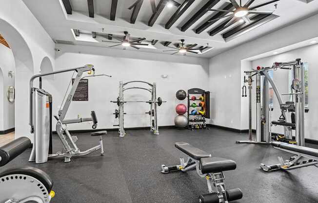 A gym with a variety of equipment including weights and a bench.