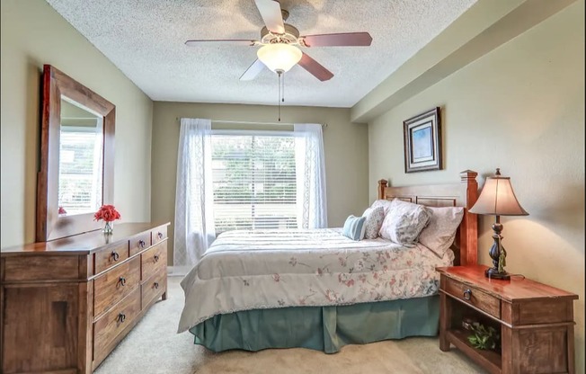 Bedroom with plush carpeting, a large window, and a ceiling fan.