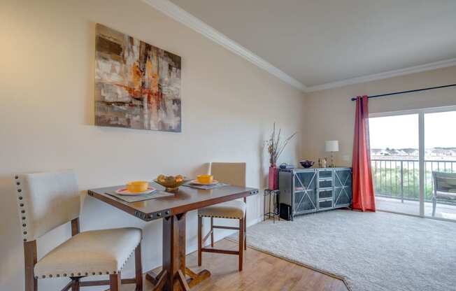 a dining area with a table and chairs and a sliding glass door leading to a balcony
