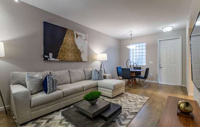 A living room with a grey couch, a coffee table, and a painting on the wall.