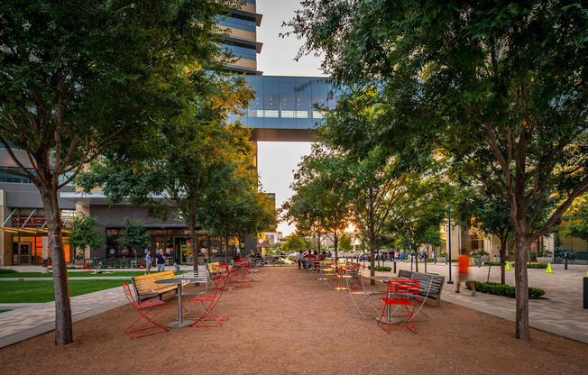 A park with benches and trees in front of a building.
