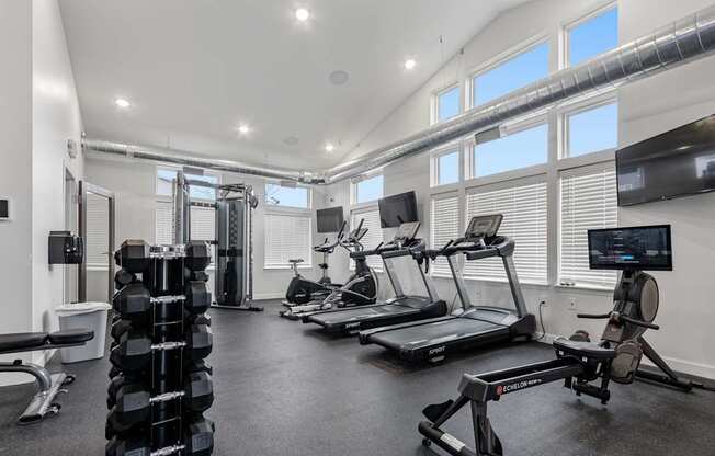 A spacious gym with a variety of equipment including treadmills, weights, and a rowing machine.