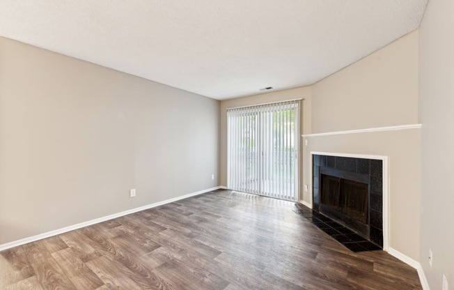 an empty living room with a fireplace and wood flooring