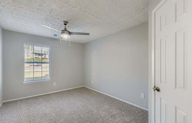 A room with a ceiling fan and a door.