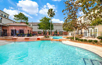 A large swimming pool in the middle of a courtyard surrounded by trees and buildings.