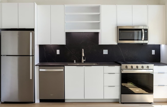 A modern kitchen with white cabinets and stainless steel appliances.