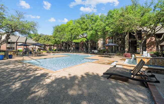 A pool surrounded by trees and a sun lounger.
