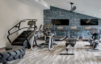 a gym with treadmills and televisions on the wall