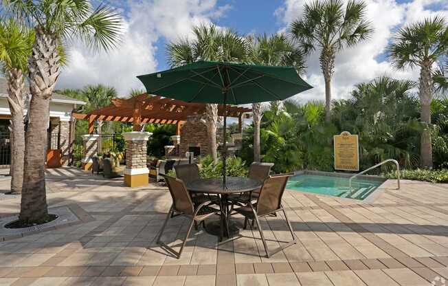 A patio with a table and chairs and a pool in the background.