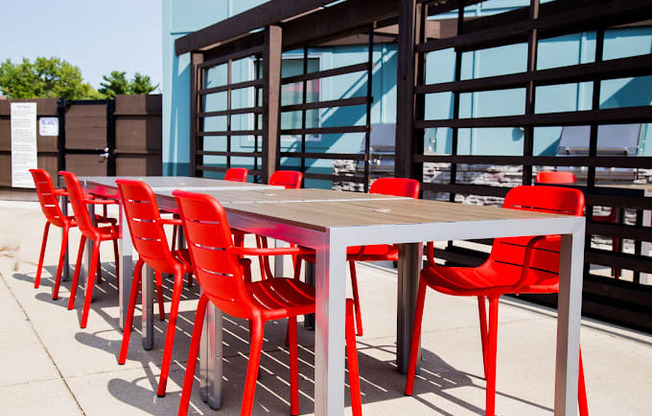 a long table with red chairs in front of a building